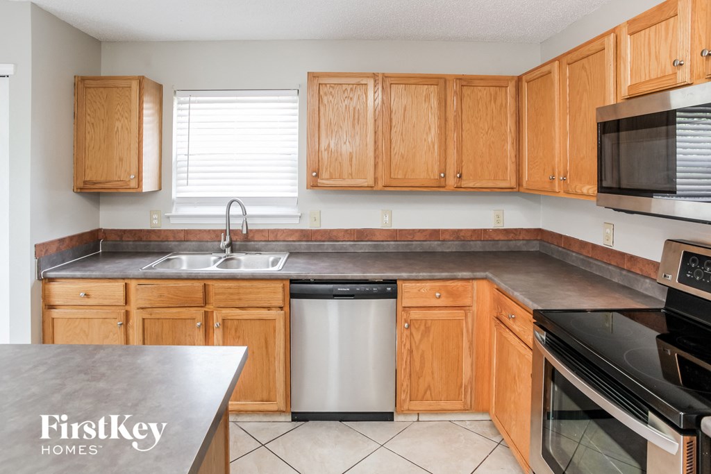 A kitchen with wooden cabinets and a stainless steel dishwasher.