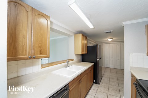 A kitchen with wooden cabinets and a black refrigerator.