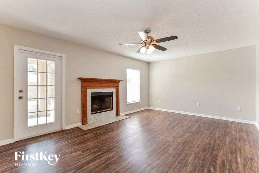 an empty living room with a fireplace and a ceiling fan