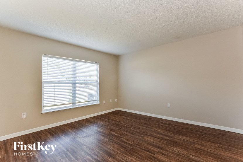 an empty living room with wood flooring and a window