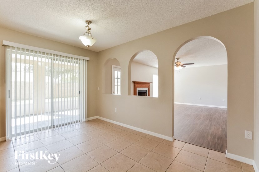 an empty living room with a sliding glass door to the dining room