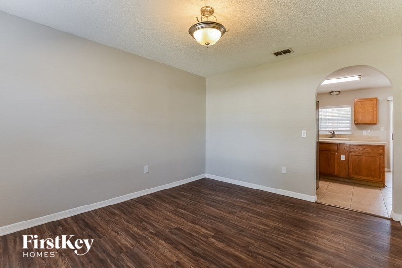 an empty living room with wood flooring and a kitchen