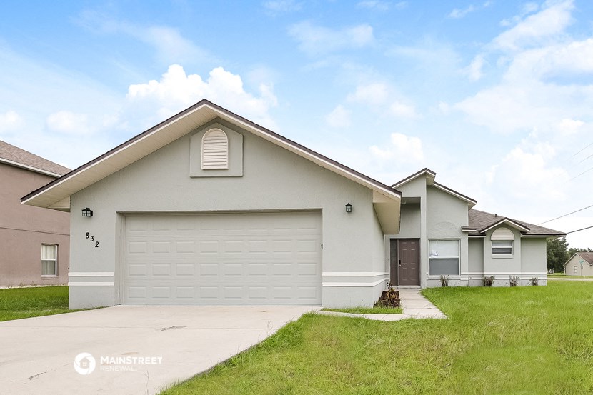 a beige house with a garage door and a lawn