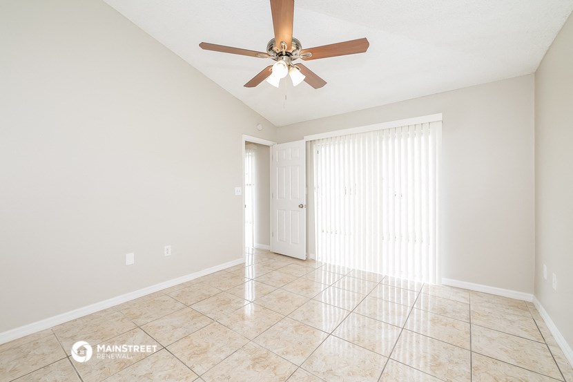 the spacious living room with ceiling fan and tile flooring