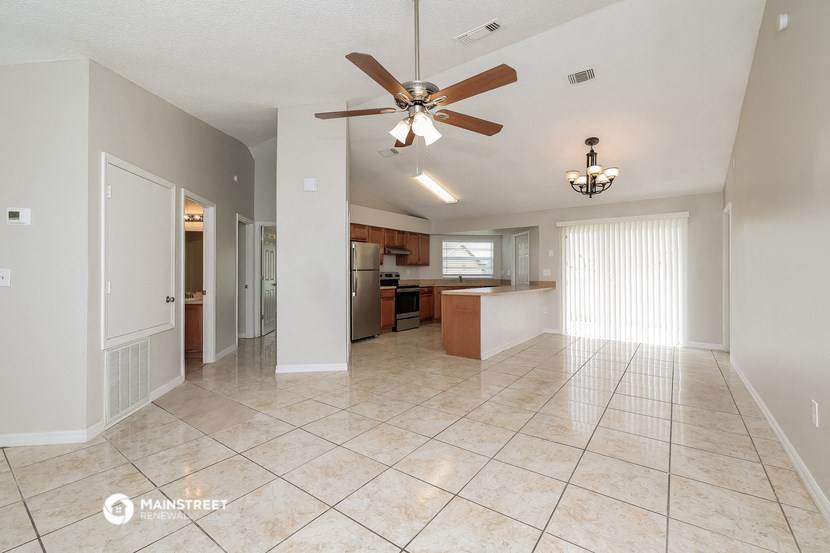 an open kitchen and living room with tile flooring and a ceiling fan