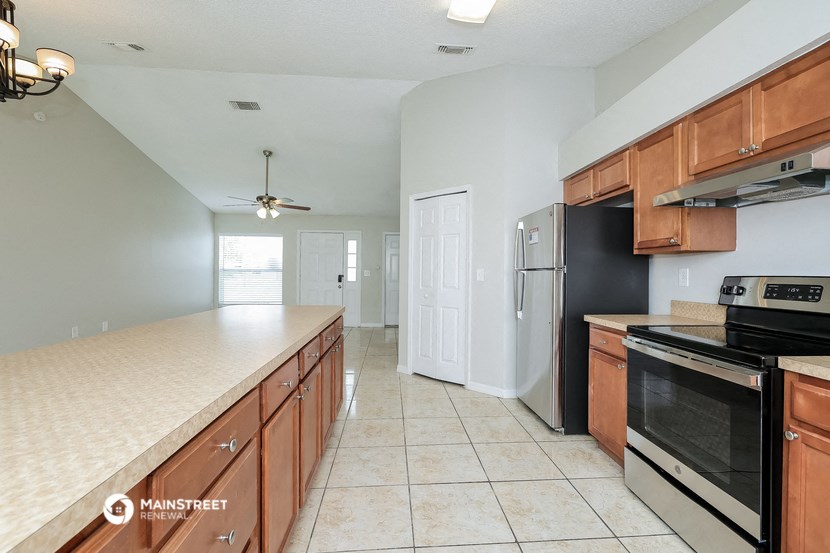 a kitchen with wooden cabinets and a counter top and a black refrigerator