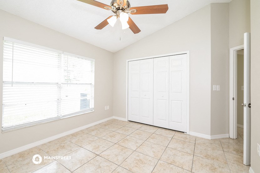 an empty living room with a ceiling fan and a window