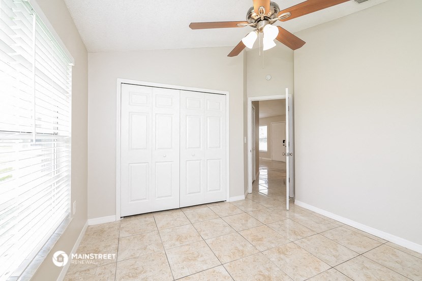 an empty living room with a ceiling fan and a door to a hallway