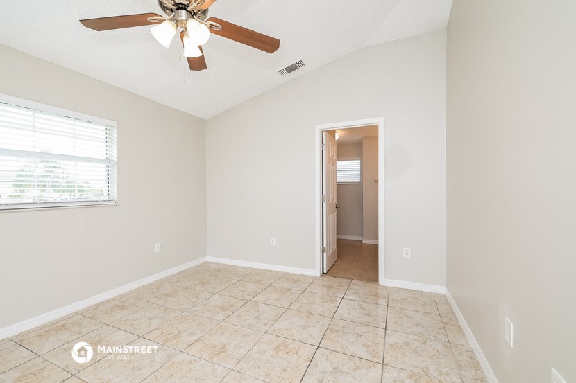 the living room of an empty home with a ceiling fan