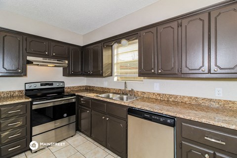 a kitchen with brown cabinets and black appliances and granite counter tops
