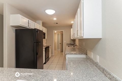 a kitchen with granite counter tops and a black refrigerator