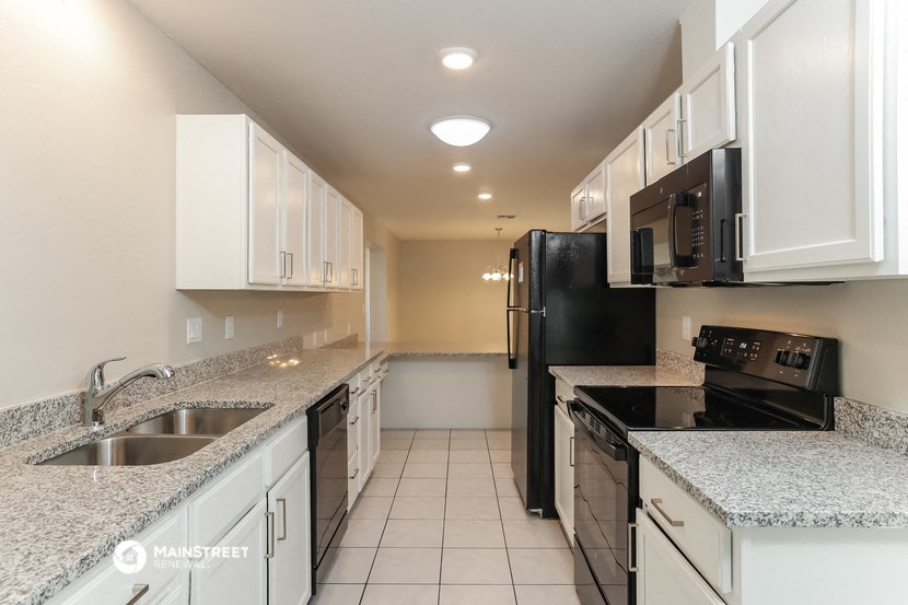 a kitchen with granite counter tops and a black refrigerator