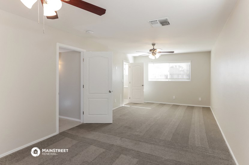 a living room with a ceiling fan and a door to a closet