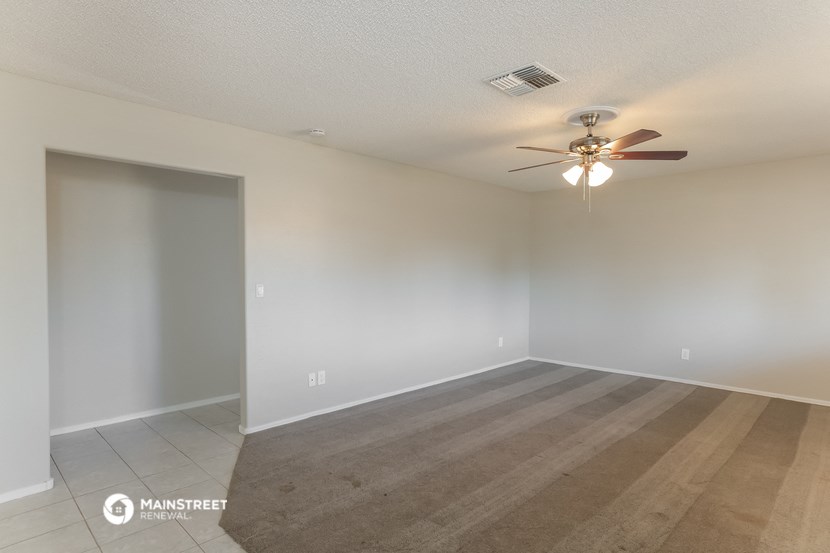 an empty living room with a ceiling fan