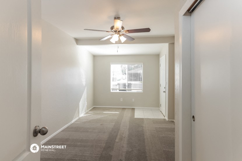 an empty hallway with a ceiling fan and a window