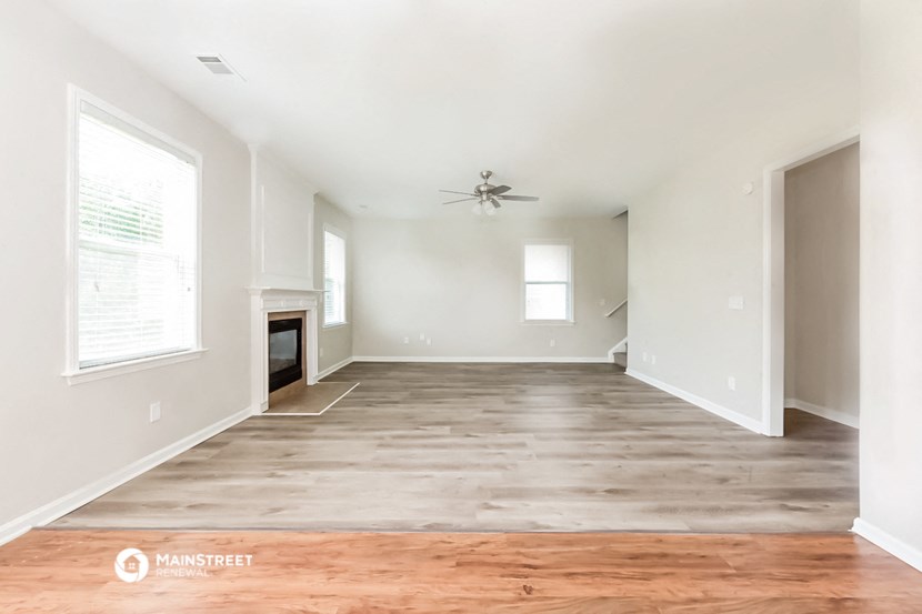 an empty living room with wood flooring and a ceiling fan