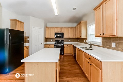 a kitchen with wooden cabinets and white counter tops and black appliances