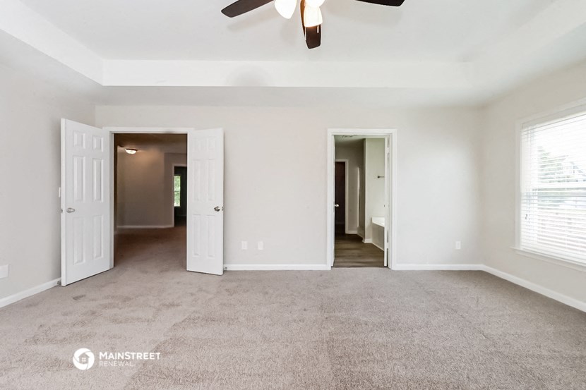 an empty living room with white walls and a ceiling fan