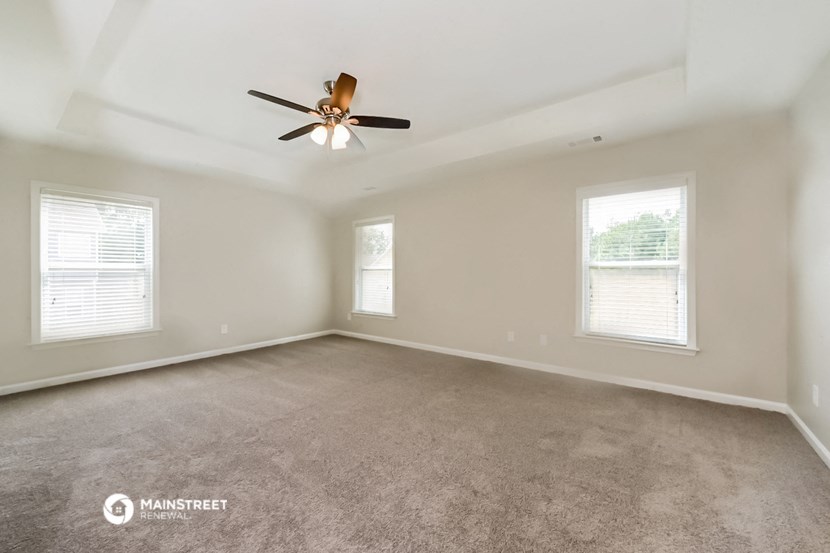 an empty living room with a ceiling fan and two windows