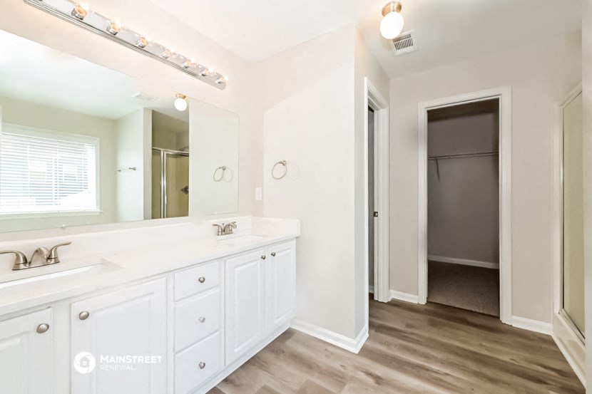 a bathroom with a sink and a mirror and a door to a closet