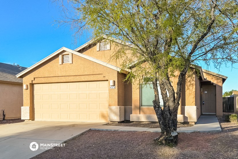 a tan brick house with a garage door and a tree