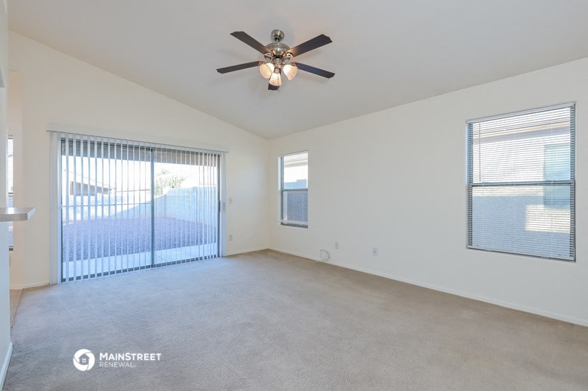 an empty living room with a ceiling fan and a large window