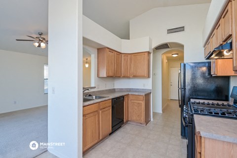 a kitchen with wooden cabinets and a black refrigerator and a sink