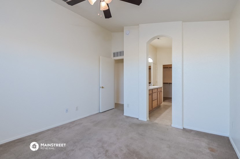 an empty living room with white walls and a kitchen