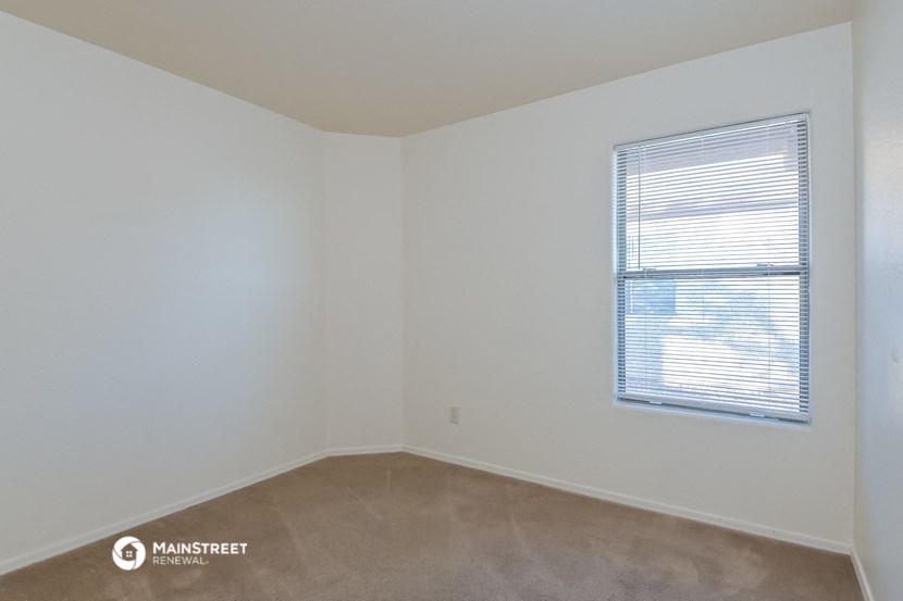 a bedroom with a window and white walls and carpet