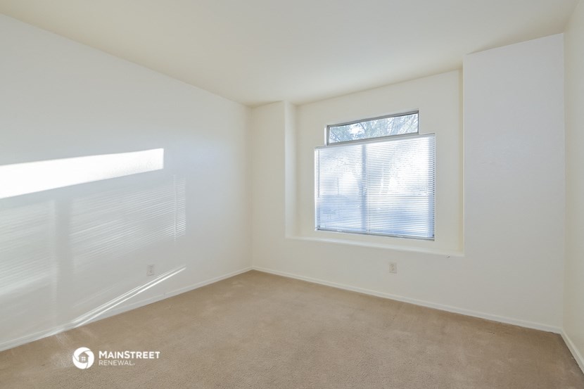 a spacious living room with two windows and carpeting
