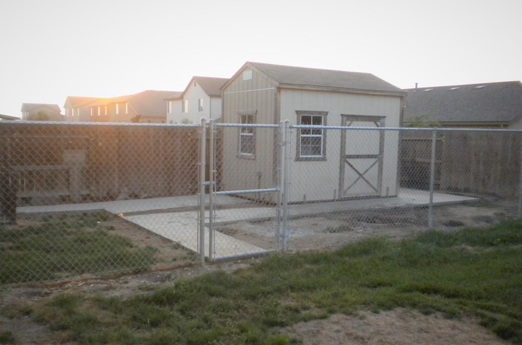 a house behind a chain link fence and a backyard with a yard and a fence