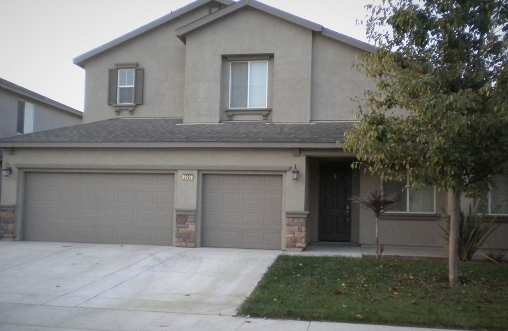 a house with two garage doors in front of a driveway