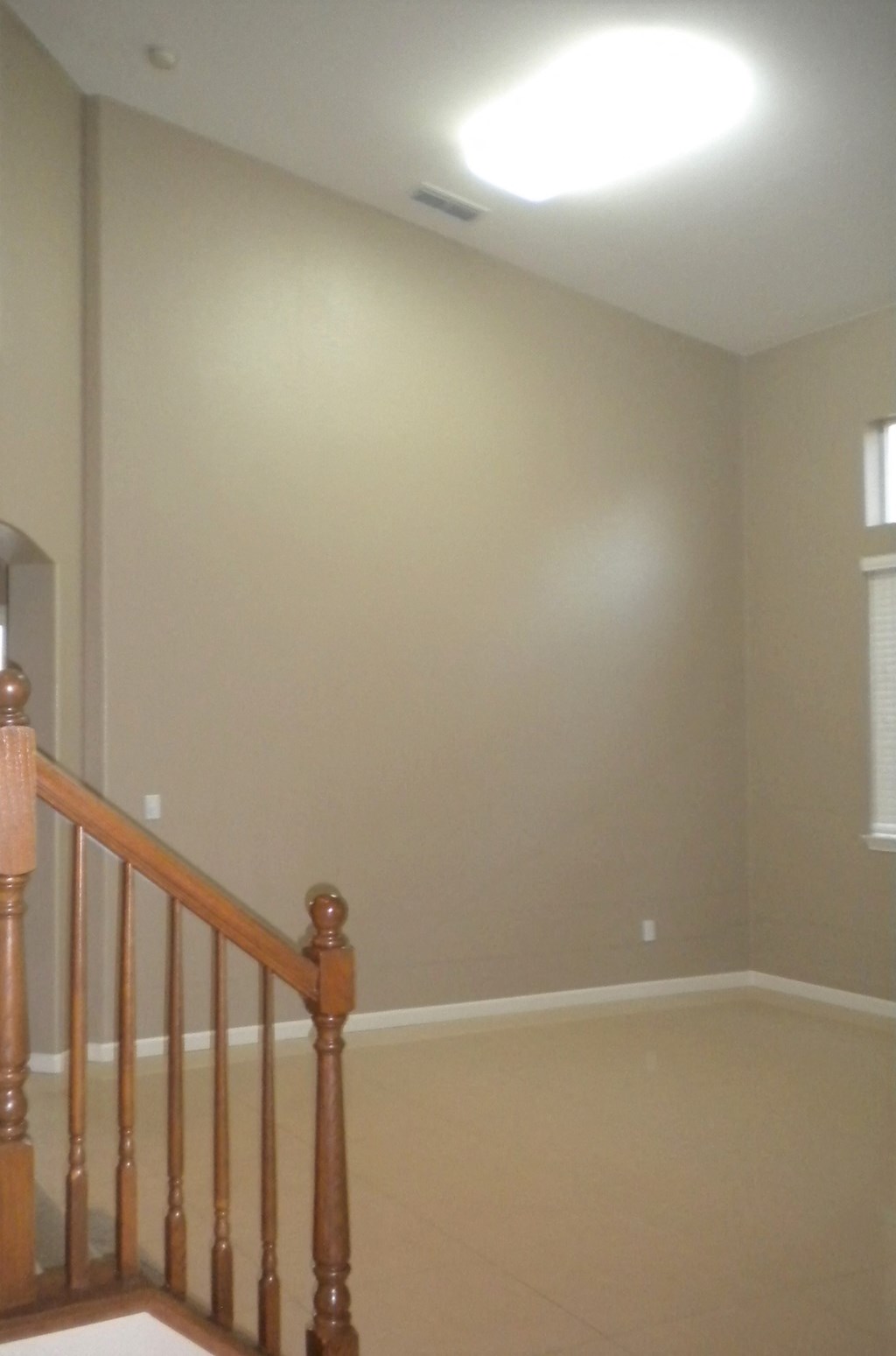 an empty living room with a staircase and a ceiling light
