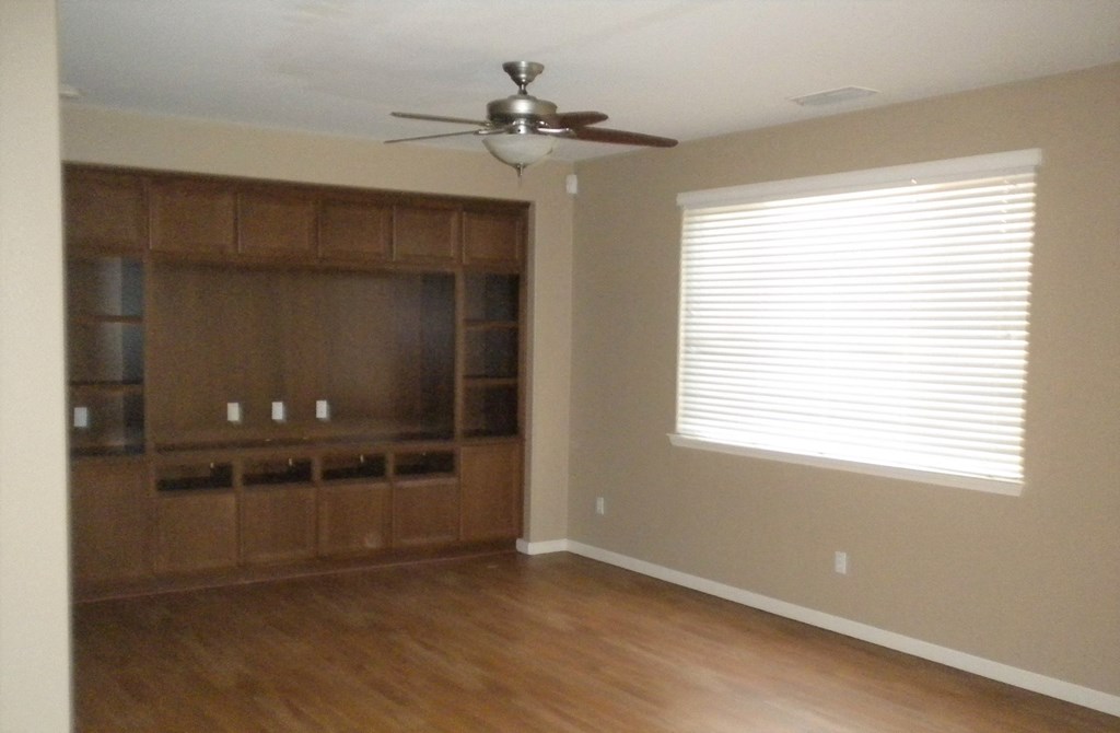 an empty living room with a ceiling fan