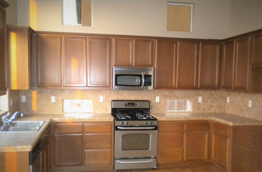 an empty kitchen with wooden cabinets and stainless steel appliances