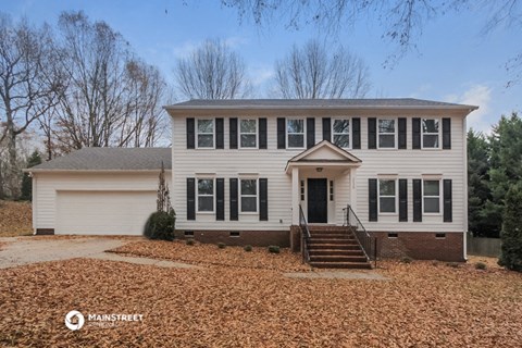 a white house with black shutters and a gravel driveway