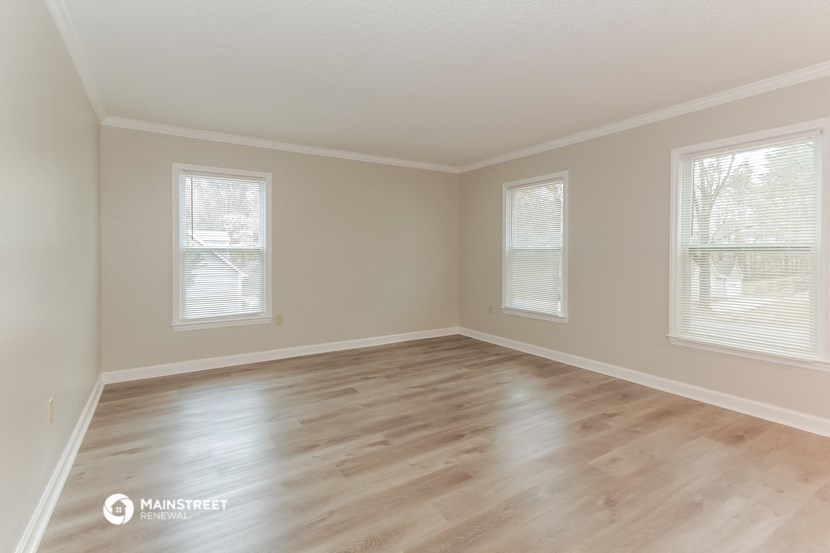 the spacious living room with wood floors and windows
