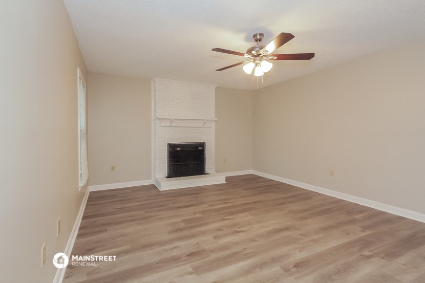 the spacious living room with fireplace and ceiling fan