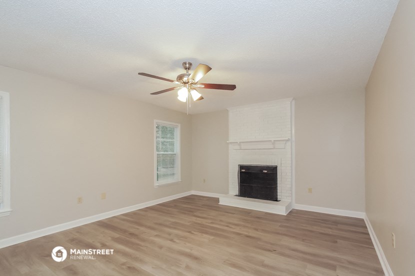 the spacious living room with fireplace and ceiling fan
