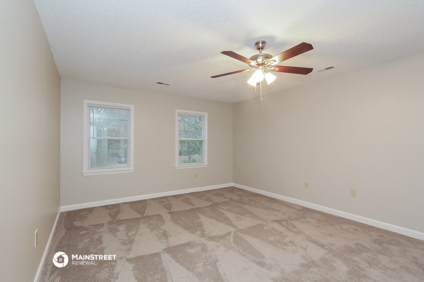 the spacious living room of a house with a ceiling fan