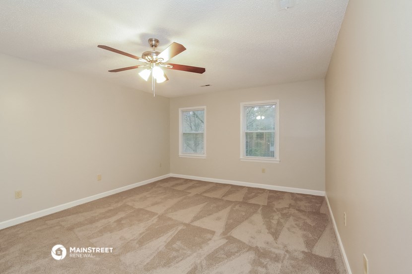 the spacious living room with carpet and a ceiling fan