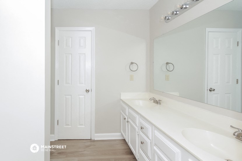 a white bathroom with two sinks and a large mirror