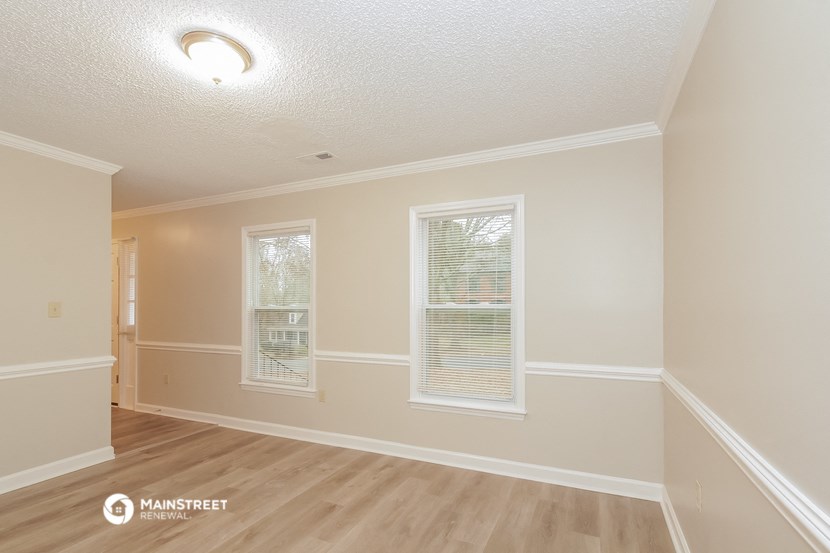 the living room and dining room of a house with white walls and wood floors