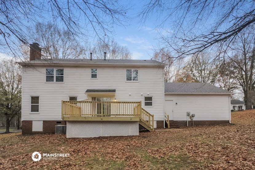 a white house with a deck on the side of a yard