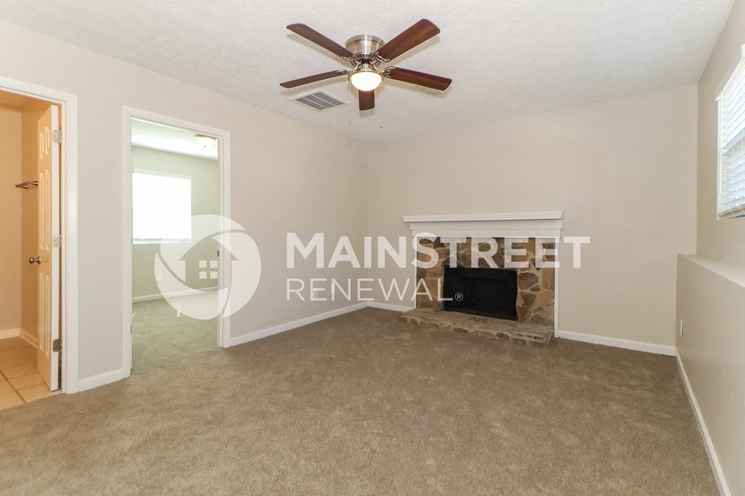 a living room with a fireplace and a ceiling fan