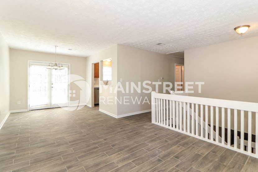 a white and gray living room with a white staircase and a window