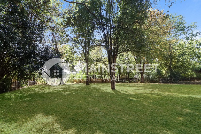 a large grassy area with trees and a building in the distance