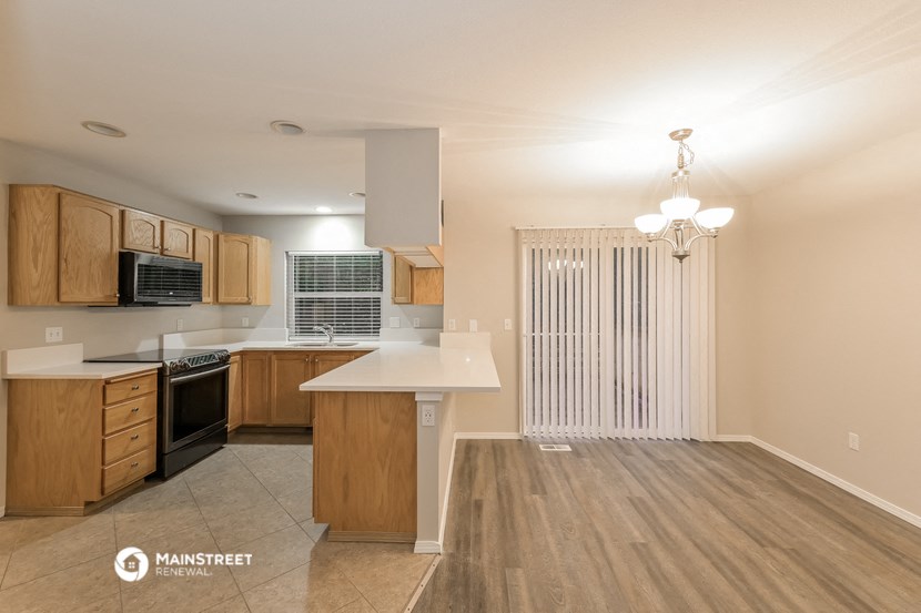 a kitchen and living room with wood flooring and a window with a white blind
