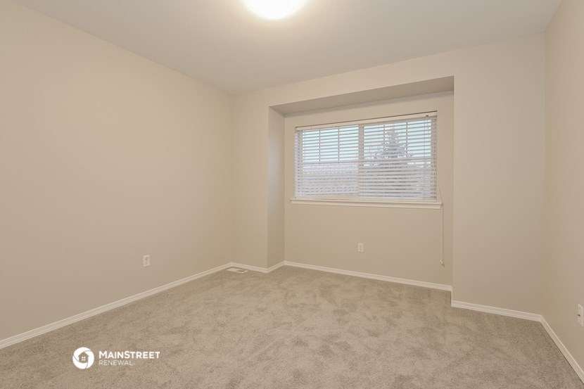 a bedroom with a window and a carpeted floor