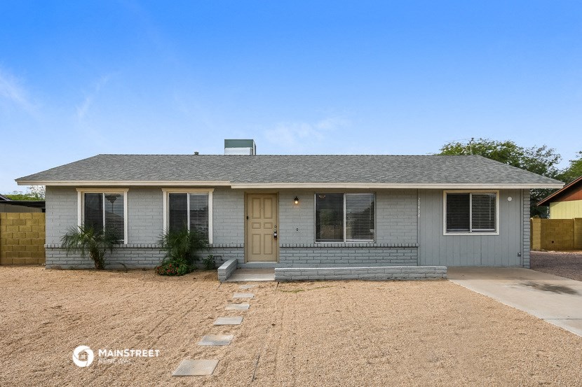 a small gray house with a gravel driveway